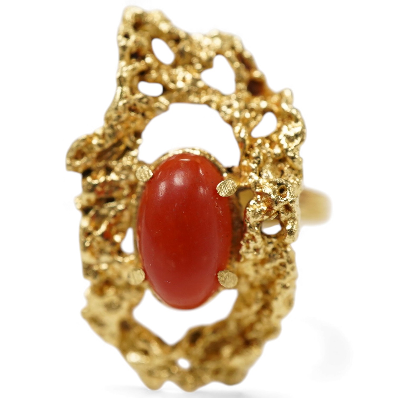 A gold and coral ring, 1970s, of textured design, set with a coral cabochon, mounted in gold, size N1/2, stamped 18K, gross weight approximately 7 grams